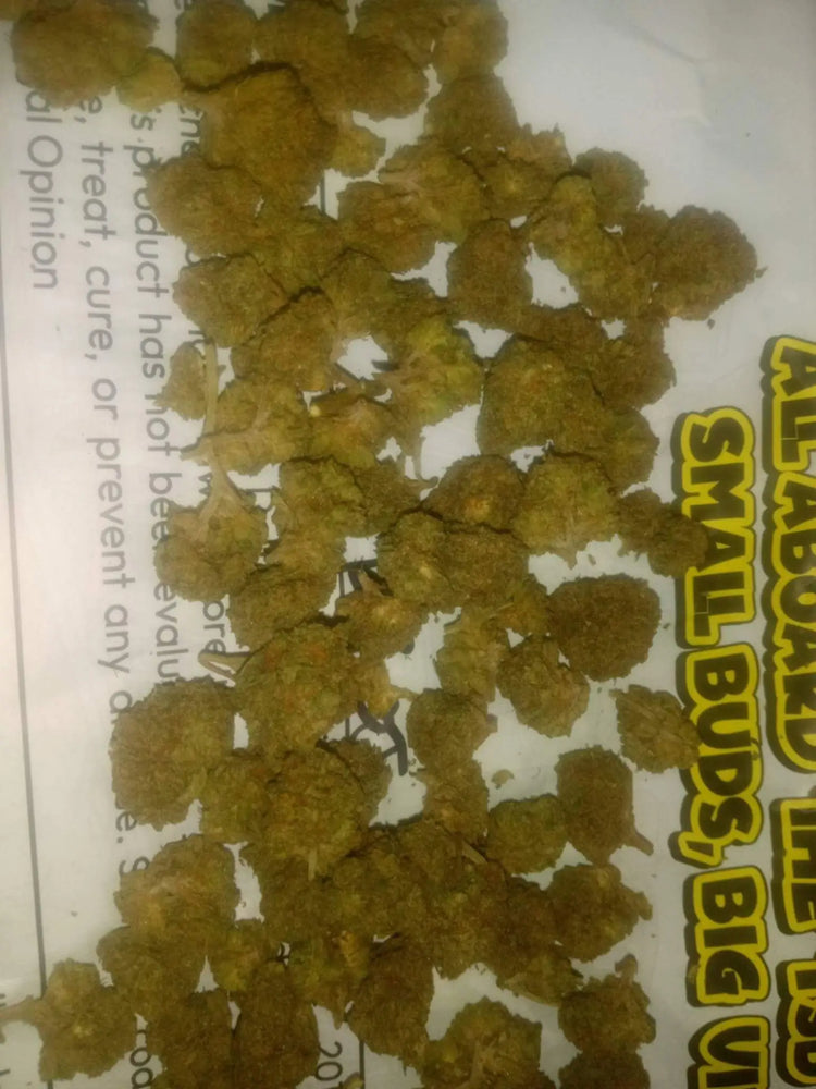 Golden-brown dense thca small buds cannabis flower scattered on white paper with bold yellow text for quarter pound review