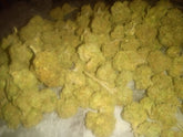 A dense pile of golden-yellow thca small buds flower with a frosty textured surface in a quarter pound review